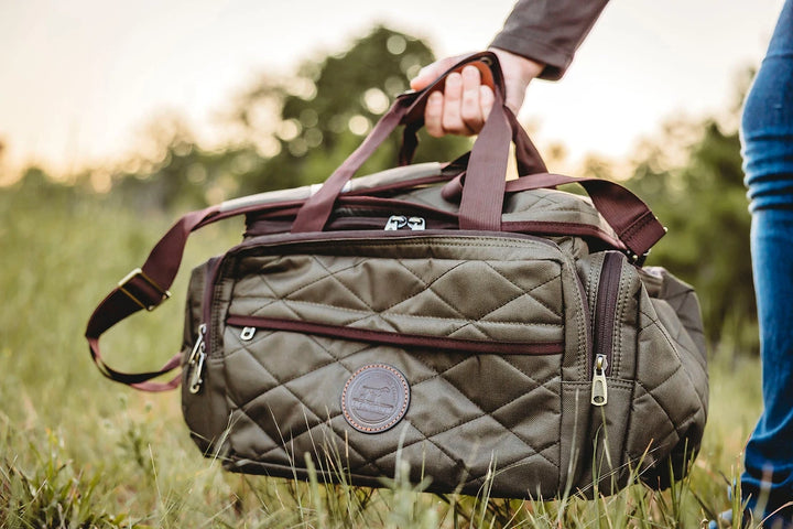 a person carrying a duffel bag in a field