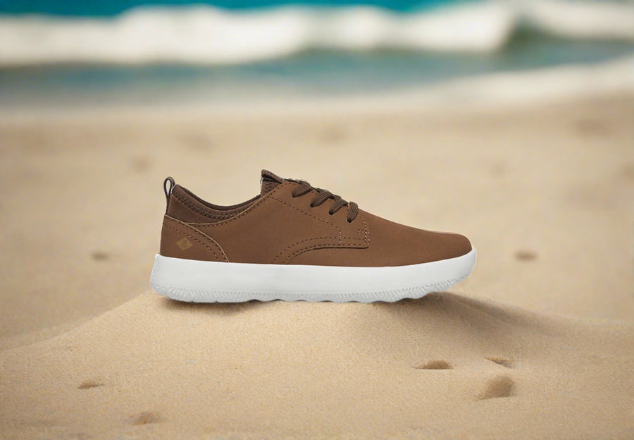 a pair of brown shoes sitting on top of a sandy beach