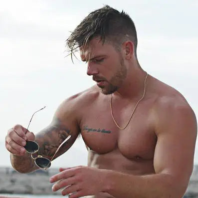 a shirtless man holding a pair of sunglasses