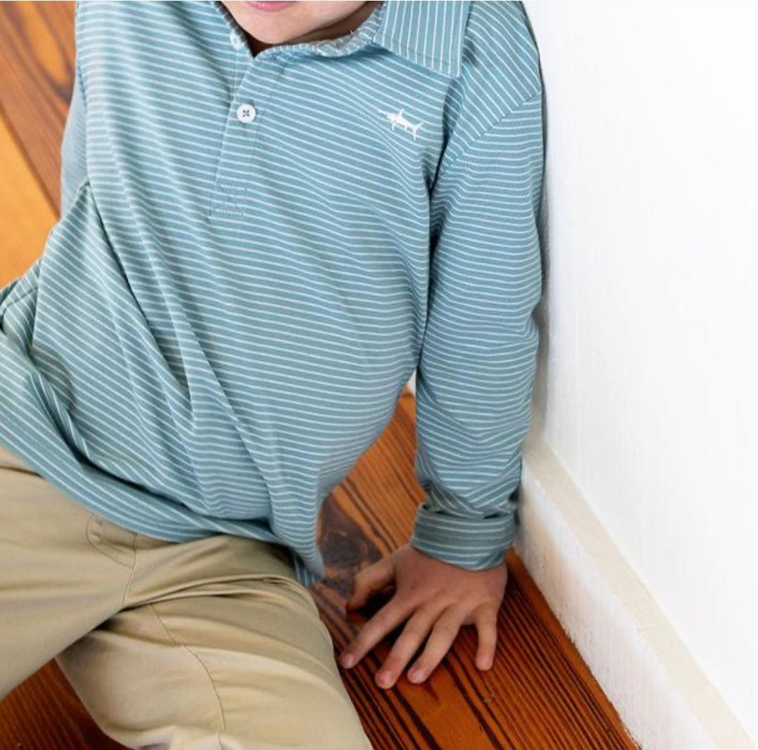 a young boy sitting on the floor with his hands on his knees